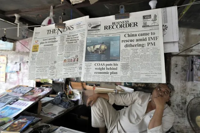 A vendor sits beside a copy of a morning newspaper which reports missing Titanic submersible and onboard five people, including Pakistani nationals Shahzada Dawood and his son Suleman, at a stall, in Karachi, Pakistan, Wednesday, June 21, 2023. A Canadian military surveillance aircraft detected underwater noises as a massive operation searched early Wednesday in a remote part of the North Atlantic for a submersible that vanished while taking five people down including Dawood, a well-known Pakistani businessman and his 19-year-old son to the wreck of the Titanic. (Photo by Fareed Khan/AP Photo)