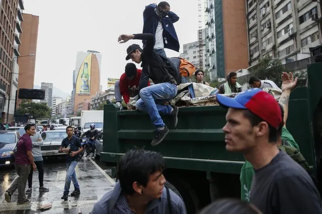 Opposition students block an avenue with a truck loaded with rocks as they protest against President Nicolas Maduro's government in Caracas February 12, 2015. Venezuelan troops blocked students during marches against Maduro on Thursday as pro-government supporters also rallied on the anniversary of 2014 protests that led to 43 deaths. (Photo by Jorge Silva/Reuters)