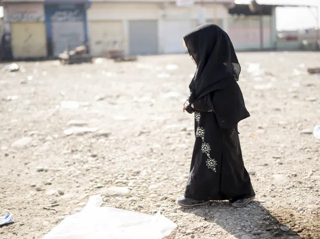 In this Sunday, November 12, 2016 photo, the daughter of a man a man who identified himself as Omar Danoun walks into a collection point for people displaced by fighting in Mosul, in Gogjali, Iraq. Danoun, who was taken into custody by Iraqi soldiers during his interview with The Associated Press, claimed he was from Mosul. The soldiers believed he was with the Islamic State group and that he seemed to speak with a Syrian accent instead of an Iraqi accent. (Photo by Nish Nalbandian/AP Photo)