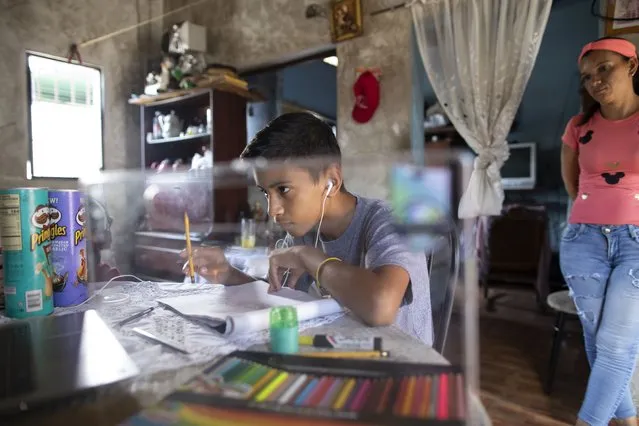Samuel Andres Mendoza looks at a picture of a Pokemon on his computer before drawing it, at his home in Barquisimeto, Venezuela, Tuesday, March 2, 2021. The 14-year-old has been selling his drawings on his Twitter account to help the family get by. (Photo by Ariana Cubillos/AP Photo)