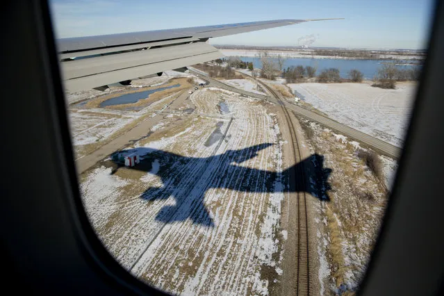 The shadow of Air Force One, with President Barack Obama aboard, casts a shadow over a snow covered field as it approaches Offutt Air Force Base in Bellevue, Neb., Wednesday, January 13, 2016, before landing. The president is en route to Omaha, Neb., where he will speak at University of Nebraska Omaha, and vist with a local family. (Photo by Carolyn Kaster/AP Photo)
