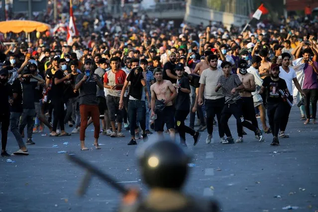 Demonstrators face security forces during an anti-government protest in Baghdad, Iraq on May 25, 2021. (Photo by Thaier Al-Sudani/Reuters)