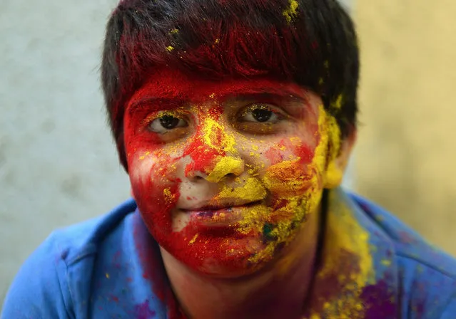 A physically challenged Indian child, smeared with gulal-coloured powder, smiles at the camera during Holi celebrations at the Society for the Edcuation of the Crippled school in Mumbai on March 4, 2015.   'Holi', the festival of colours, is a riotous celebration of the coming of spring and falls on the day after full moon annually in March.  Revellers spray coloured powder and water on each other with great gusto, whilst adults extend the hand of peace.  AFP PHOTO / PUNIT PARANJPE        (Photo credit should read PUNIT PARANJPE/AFP/Getty Images)