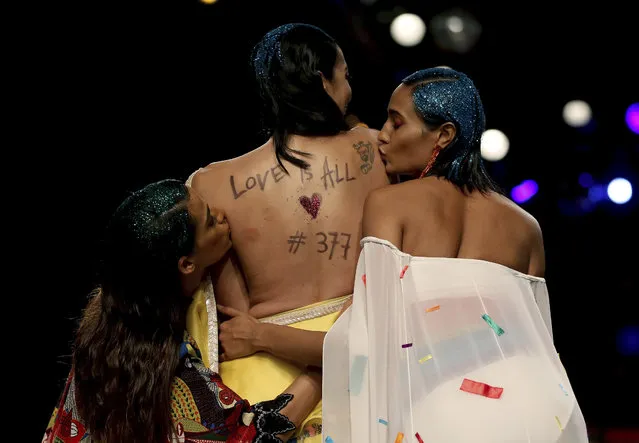 Models kiss the back of another model, with a message on her back, during the grand finale of Lotus Make-up India Fashion Week based on “Rainbow” theme, an emblem for the LGBTQ community, in New Delhi, India, Sunday, October 14, 2018. According to Fashion Design Council of India, the “Rainbow” show, wherein 40 designers showcased their creations, was a tribute to mark the historic judgement by the Supreme Court of India which struck down a colonial-era law that made homosexual acts punishable by up to 10 years in prison. (Photo by Altaf Qadri/AP Photo)