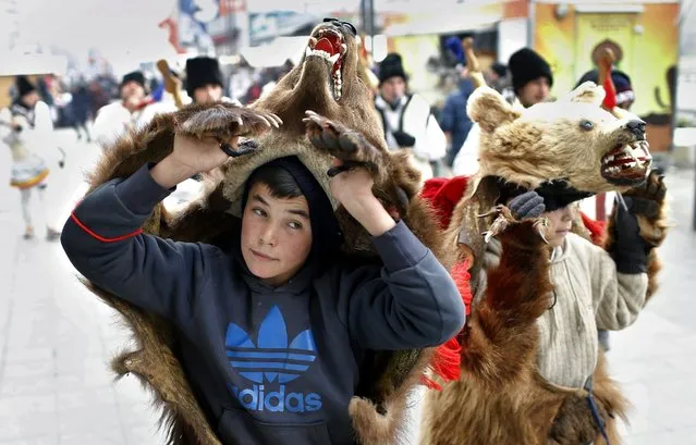 Two young Romanian men, wearing real bear fur, perform a ritual dance while their colleagues are singing Christmas songs, accompanied by ancient musical instruments, during a traditional Christmas carol show on the street in downtown Bucharest, Romania, 20 December 2016. Carol bands from Moldova county come to Bucharest to perform Christmas carols for passers-by in exchange for a small amount of money. (Photo by Robert Ghement/EPA)