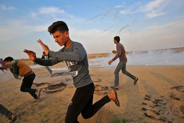 Palestinians run for cover from tear gas during clashes near the border between Israel and Khan Yunis in the southern Gaza Strip on November 9, 2018. (Photo by Said Khatib/AFP Photo)