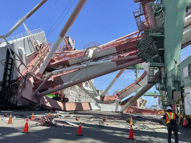 Port workers view the scene of a massive container gantry crane that toppled over Thursday, June 3, 2021, in the port of Khaohsiung, southern Taiwan. The crane fell over after a cargo ship knocked into it Thursday morning, sending it crashing to the ground in the port. (Photo by Taiwan International Ports Corporation Ltd. via AP Photo)