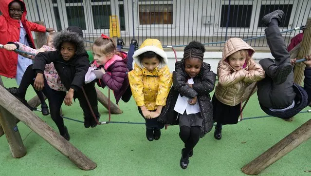 Faith, left, with some of her fellow pupils Julia, Nana, Yaw, Alexandra, Leandra, and Amariah, right play on a rope swing at the Holy Family Catholic Primary School during a break, in Greenwich, London, Wednesday, May 19, 2021. Holy Family, like schools across Britain, is racing to offset the disruption caused by COVID-19, which has hit kids from low-income and ethnic minority families hardest. (Photo by Alastair Grant/AP Photo)