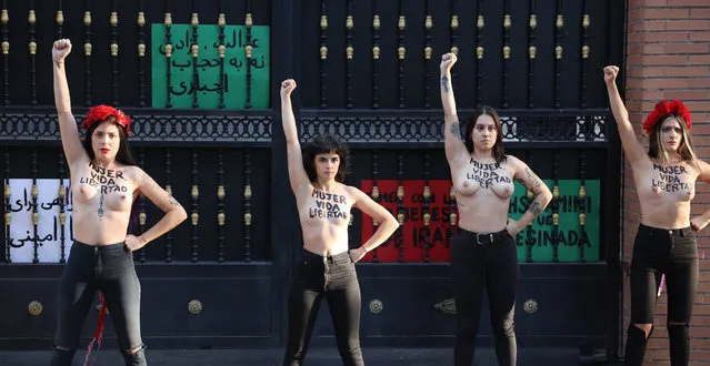 Members of the feminist activist group Femen with the words “Woman, life, freedom” written on their chests protest in support of the Irainian women and against the death of Iranian woman Mahsa Amini outside the embassy of Iran in Madrid on September 23, 2022. Mahsa Amini, 22, was on a visit with her family to the Iranian capital Tehran, when she was detained on September 13, 2022, by the police unit responsible for enforcing Iran's strict dress code for women, including the wearing of the headscarf in public. She was declared dead on September 16, 2022 by state television after having spent three days in a coma. (Photo by Thomas Coex/AFP Photo)