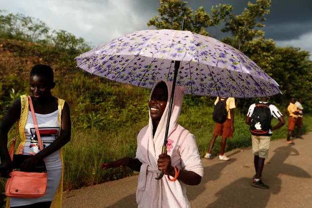 Poshia, 16, who said she is a fashion designer smiles as she holds an umbrella for her relative near  princess town, Ghana on November 23, 2018. (Photo by Zohra Bensemra/Reuters)