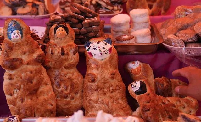 A woman sells the traditional Tantawawas, a bread shaped as cholitas and cats offered to the dearly departed on the Day of the Dead, at the street market in La Paz, Bolivia, Monday, October 31, 2022. (Photo by Juan Karita/AP Photo)
