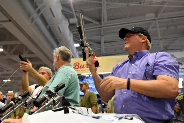 Dave Verner looks at pistols and scopes in the trade booth area during the National Rifle Association's annual meeting in Nashville, Tennessee April 11, 2015. (Photo by Harrison McClary/Reuters)