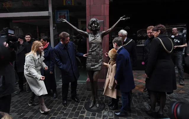 Robert Willis, (centre L) a son of late British singer and TV personality Cilla Black, poses alongside a bronze statue of his mother, created by artists Emma Rodgers and Andy Edwards, after it was unveiled outside the Cavern Club in Liverpool, north- west England on January 16, 2017. Black, who grew up in Liverpool and enjoyed a 40- year career in show business, died on August 1, 2015, in Spain after suffering a stroke at the age of 72. Born Priscilla White, Black was championed by The Beatles and later became one of Britain' s best- loved television presenters. (Photo by Paul Ellis/AFP Photo)