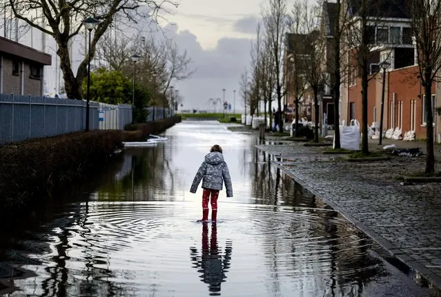 A child stands in a flooded street near the Markermeer after the first storm of this year, which was named Henk, in Hoorn, the Netherlands, 03 January 2024. (Photo by Robin Van Lonkhuijsen/EPA)