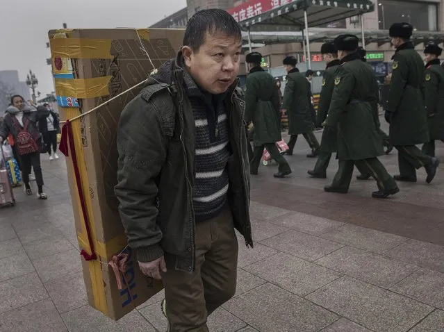 A Chinese carries a television set on his back as he arrives to board a train at Beijing Railway Station on January 26, 2017 in Beijing, China. (Photo by Kevin Frayer/Getty Images)