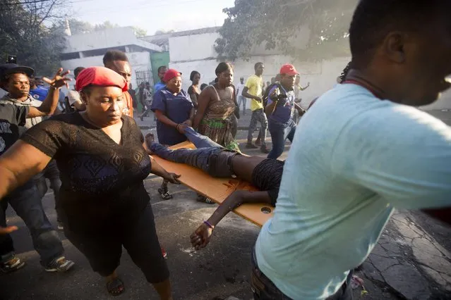 Demonstrators carry the body of a person killed during the violent clashes between the police and demonstrators near the national palace, during a protest to demand the resignation of President Jovenel Moise and demanding to know how Petro Caribe funds have been used by the current and past administrations, in Port-au-Prince, Haiti, Saturday, February 9, 2019. (Photo by Dieu Nalio Chery/AP Photo)