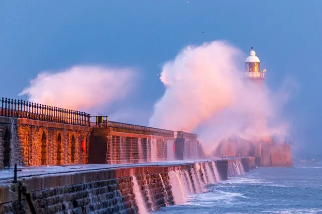 Large waves hit Tynemouth Pier in United Kingdom on January 14, 2024 during sunset, colour was reflected into the waves smashing over the pier. (Photo by John Fatkin/Cover Images)