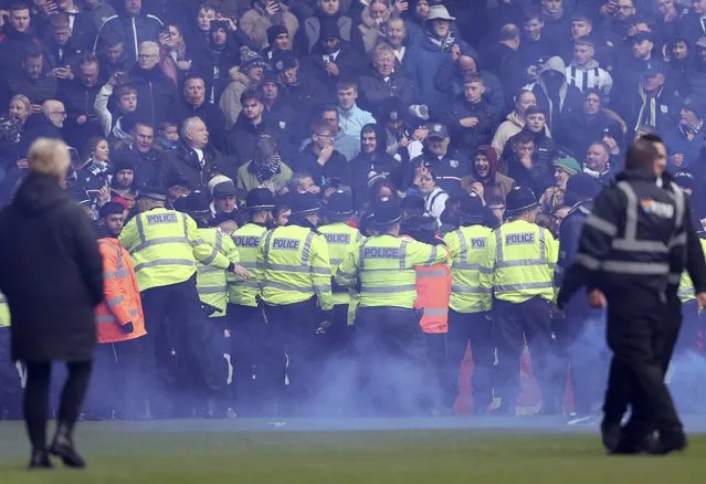 Police in front of fans with blue flare during the Emirates FA Cup Fourth Round match between West Bromwich Albion and Wolverhampton Wanderers at The Hawthorns on January 28, 2024 in West Bromwich, England. (Photo by Neal Simpson/Sportsphoto/Allstar via Getty Images)