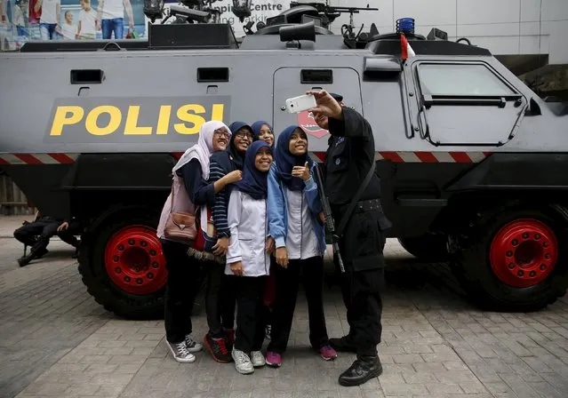 An anti-riot policemen holding a weapon takes a picture with students near an armoured car as he stands guard for a commemorative ceremony for the 1955 Asia-Africa Conference in Bandung, West Java province, April 23, 2015. (Photo by Reuters/Beawiharta)