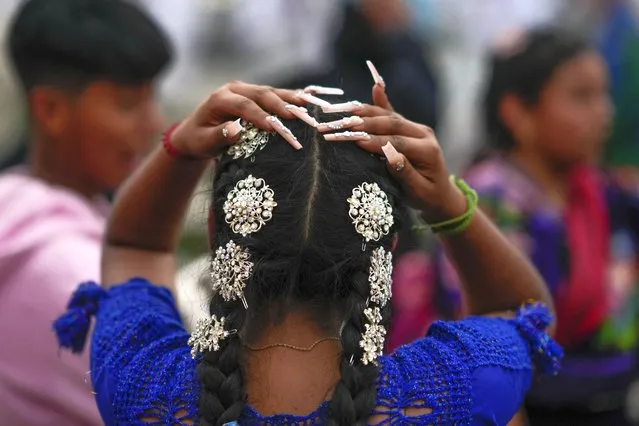 A Purepecha Indigenous woman adjusts her hair after arriving to Ocumicho, having walked from Erongaricuaro with a group carrying a flame that the community had kept alive for one year, in Michoacan state, Mexico, Wednesday, January 31, 2024. A new flame will be lit in Ocumicho at the “New Fire” ceremony on Feb. 2 to mark the new year, after extinguishing the old fire on Feb. 1 which is considered an orphan day that belongs to no month and is used for mourning and renewal. (Photo by Eduardo Verdugo/AP Photo)