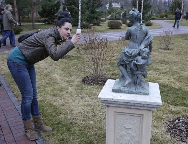 A woman takes a picture of a statue as anti-government protesters and journalists walk on the grounds of the Mezhyhirya residence of Ukraine's President Viktor Yanukovich in the village Novi Petrivtsi outside Kiev February 22, 2014. (Photo by Konstantin Chernichkin/Reuters)