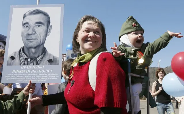 A woman with a child holds picture of World War Two soldier as she takes part in the Immortal Regiment march during the Victory Day celebrations in Divnogorsk, Russia, May 9, 2015. (Photo by Ilya Naymushin/Reuters)
