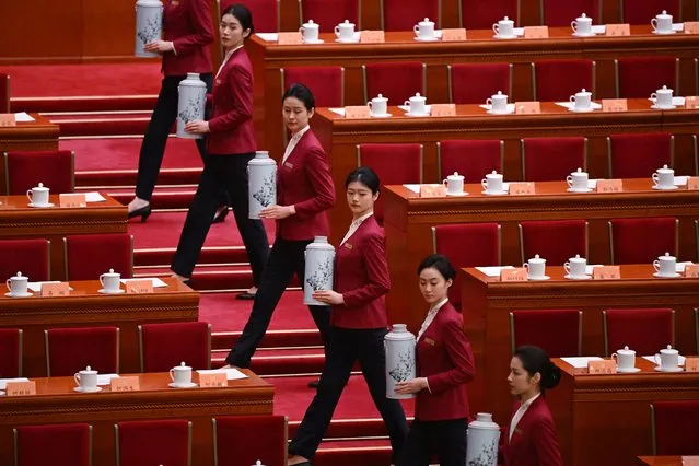 Attendants carry flasks of hot tea for Chinese leaders before the closing session of the Chinese People's Political Consultative Conference at the Great Hall of the People in Beijing on March 10, 2024. (Photo by Greg Baker/AFP Photo)