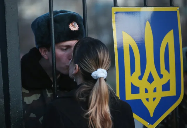 Oleg, a Ukrainian soldier at the Belbek military base, kisses his girlfriend Svetlana through the gates of the base entrance on March 3, 2014 in Lubimovka, Ukraine. Tensions at the base, where between 100 and 200 Ukrainian soldiers are stationed, are high as a 4pm deadline reportedly given by Russian troops for the Ukrainians to surrender passed and locals feared the Russians might attack tonight. (Photo by Sean Gallup/Getty Images)