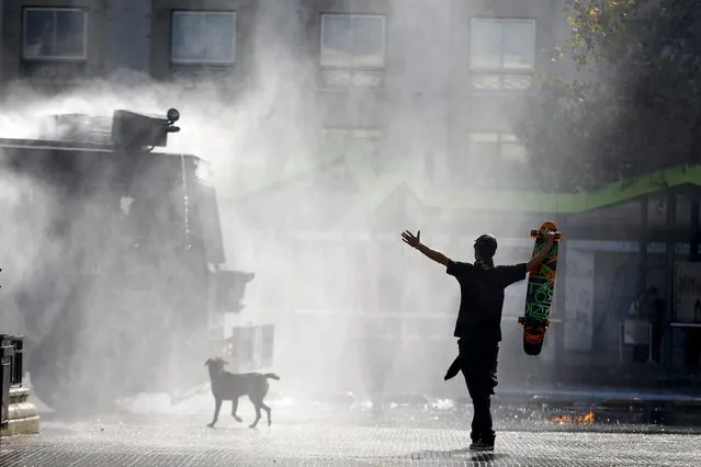 A protester holds up his skateboard in front of a riot police vehicle as they clash during a demonstration to demand changes in the education system at Santiago, May 14, 2015. (Photo by Ivan Alvarado/Reuters)