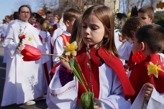 A child looks at a flower during a Palm Sunday procession in Bucharest, Romania, on March 24, 2024. (Photo by Andreea Campeanu/Reuters)
