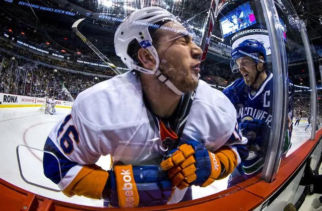 New York Islanders' Matt Donovan, left, is checked into the glass by Vancouver Canucks' Henrik Sedin, of Sweden, during first period NHL hockey action in Vancouver, British Columbia, on March 10, 2014. (Photo by Darryl Dyck/The Canadian Press)