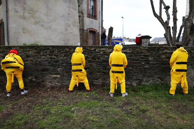 People dressed in costume urinate on a wall during the annual UNESCO listed carnival of Granville, northwestern France, on February 26, 2017. (Photo by Charly Triballeau/AFP Photo)