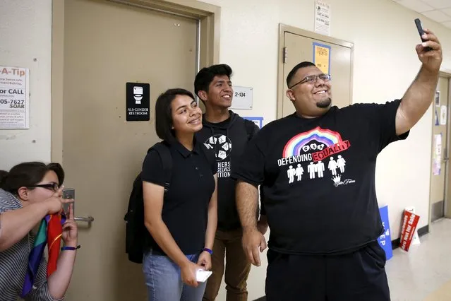 Monique Garcia, 17, (L-R), Juliet Dominguez, 15, Johnny Ramos, 18, and Jose Lara, 34, Dean of Students & GSA Advisor, pose for a selfie in front of the first gender-neutral restroom in the Los Angeles school district, which they helped lobby for, at Santee Education Complex high school in Los Angeles, California, U.S., April 18, 2016. (Photo by Lucy Nicholson/Reuters)