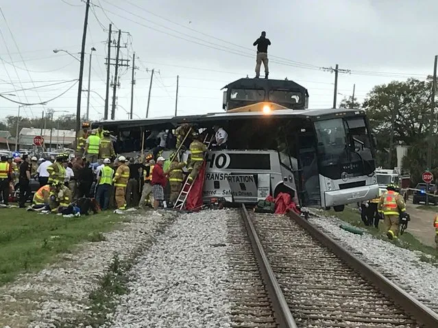 Biloxi firefighters assist injured passengers after their charter bus collided with a train in Biloxi, Miss., Tuesday, March 7, 2017. Biloxi city spokesman Vincent Creel says emergency responders were still removing injured people from the bus more than 30 minutes after the crash. (Photo by John Fitzhugh/The Sun Herald via AP Photo)