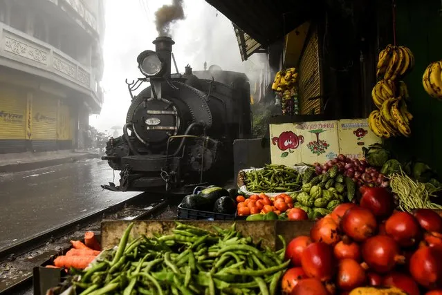 A Darjeeling Himalayan Railway steam train, which runs on a 2 foot gauge railway and is a UNESCO World Heritage Site, passes by a market in Ghum, India, June 27, 2019. (Photo by Ranita Roy/Reuters)