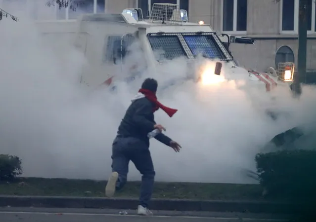 A rioter throws a brick at a police vehicle during clashes after a protest against European anti-coronavirus measures, in Brussels, Belgium, 23 January 2022. Tens of thousands of people were expected to a protest against the way the EU governments imposed “disproportionate measures that violate human rights”, as organiser 'Europeans United' puts it, to curb the Omicron variant wave of the Sars-Cov-2 coronavirus. (Photo by Stephanie Lecocq/EPA/EFE)