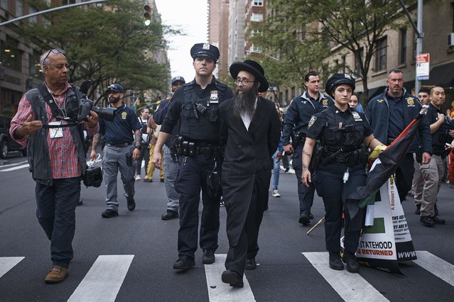 Police escort a pro-Palestinian ultra-Orthodox Jewish demonstrator after detaining him near the Metropolitan Museum of Art where the Met Gala is being held, Monday, May 6, 2024, in New York. (Photo by Andres Kudacki/AP Photo)