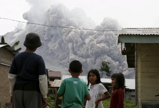 Children gather as they look at ash spewing from Mount Sinabung volcano during an eruption as seen from Kuta Tengah village in Karo Regency, North Sumatra province, Indonesia June 26, 2015. (Photo by Reuters/Beawiharta)