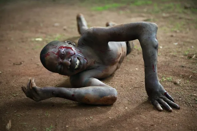 Kevin, a man accused of being a thief by civil servants at the Work Inspection office, lays in pain after being attacked by a man with a machete and sticks, in plain view of others, in Bangui, Central African Republic, Friday, April 18, 2014. Foreign journalists intervened and stopped the beating, as the crowd shouted “he is a thief, he must die”. (Photo by Jerome Delay/AP Photo)