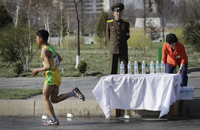 A North Korean military soldier stands on duty while a participant of the Pyongyang marathon runs past a water station on Sunday, April 9, 2017, in Pyongyang, North Korea. (Photo by Wong Maye-E/AP Photo)