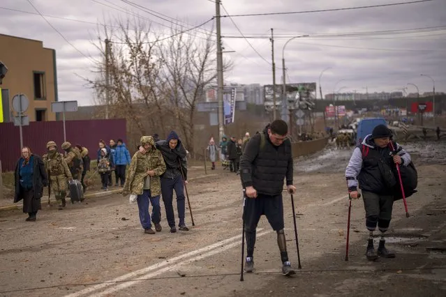 People with disabilities and injured soldiers walk after crossing the Irpin river on the outskirts of Kyiv, Ukraine, Saturday, March 5, 2022. (Photo by Emilio Morenatti/AP Photo)