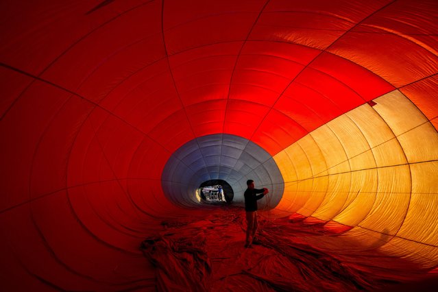 A crew member adjusts the lines in a hot air balloon at an international balloon festival at Laguna Caren Park, in Santiago, Chile, Saturday, January 13, 2024. (Photo by Esteban Felix/AP Photo)