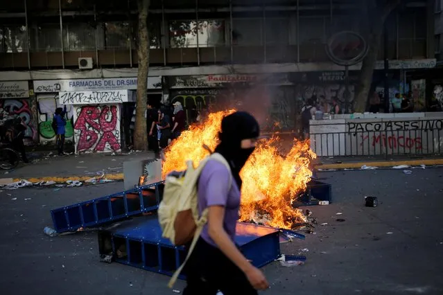 A demonstrator passes a barricade on fire during a protest against Chile's state economic model in Santiago October 21, 2019. (Photo by Edgard Garrido/Reuters)