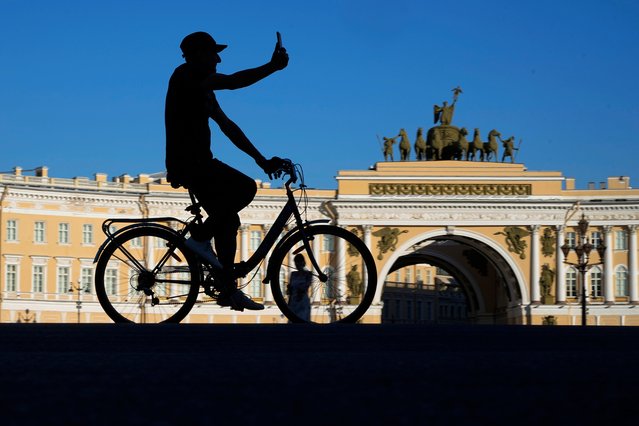 A man takes a video selfie, riding a bicycle at the Palace Square in St. Petersburg, Russia, Wednesday, July 10, 2024. (Photo by Dmitri Lovetsky/AP Photo)