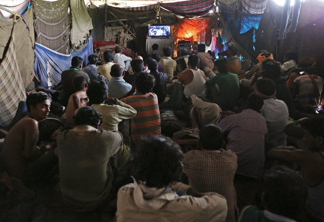 People watch a movie in a makeshift cinema located under a bridge in the old quarters of Delhi, India May 25, 2016. (Photo by Cathal McNaughton/Reuters)