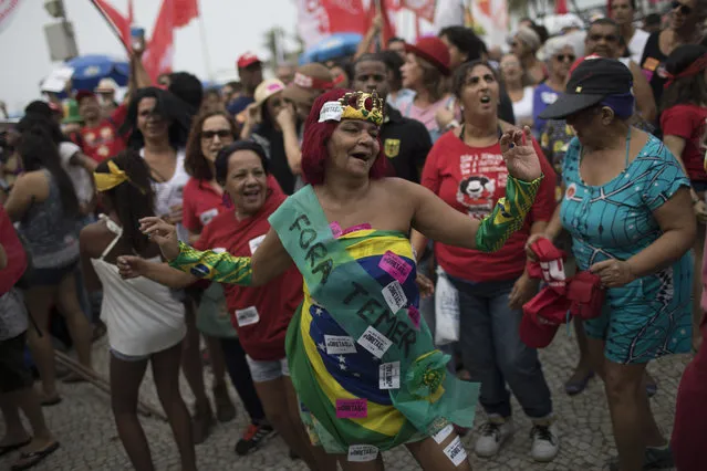 A woman wearing a costume that reads in Portuguese “Temer out” dances during a protest against Brazil's president Michel Temer at Copacabana beach in Rio de Janeiro, Brazil, Sunday, May 28, 2017. People gathered on Copacabana beach ahead of a concert by Brazilian musical performers calling for new presidential elections while pressure mounts on the country's leader to resign amid corruption allegations. (Photo by Leo Correa/AP Photo)