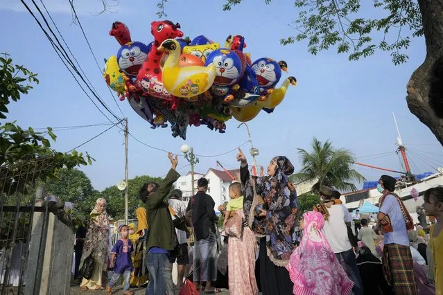 A woman buys a balloon after Eid al-Fitr prayers to mark the end of the holy fasting month of Ramadan at Sunda Kelapa port in Jakarta, Indonesia, Monday, May 2, 2022. (Photo by Tatan Syuflana/AP Photo)