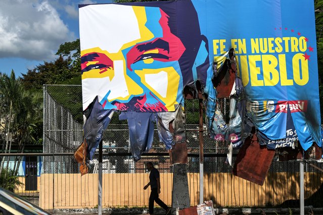 A man walks under a giant billboard with the image of Venezuelan President Nicolas Maduro, which was vandalized during strong protests against the results of Venezuela's presidential election in Valencia, Carabobo State, Venezuela, on July 31, 2024. Venezuelan President Nicolas Maduro said Wednesday he was willing to share evidence of his election win, with international pressure mounting for him to back up a disputed victory that has sparked deadly protests. (Photo by Yuri Cortéz/AFP Photo)