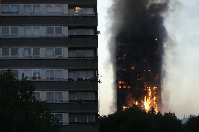 Smoke and flames rise from a building on fire in London, Wednesday, June 14, 2017. Metropolitan Police in London say they're continuing to evacuate people from a massive apartment fire in west London. The fire has been burning for more than three hours and stretches from the second to the 27th floor of the building. (Photo by Matt Dunham/AP Photo)