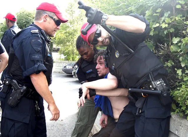 Police detain a protestor prior to a rally for Canadian Prime Minister Stephen Harper in Montreal, Quebec, August 2, 2015. Canadian Prime Minister Harper on Sunday called a parliamentary election for October 19, kicking off a marathon 11-week campaign, the longest federal election campaign in recent history. (Photo by Christinne Muschi/Reuters)